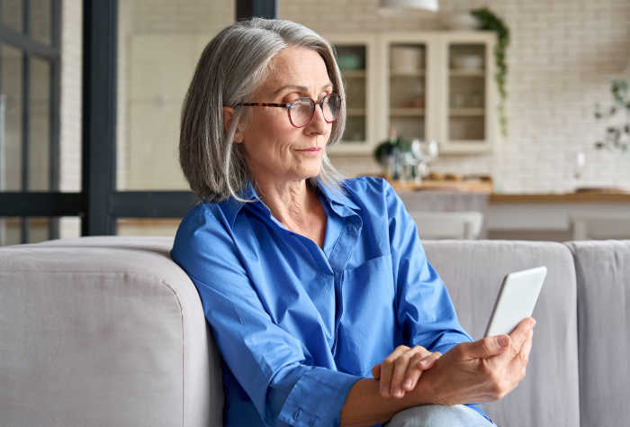 Woman sitting on a couch and reading information on a tablet